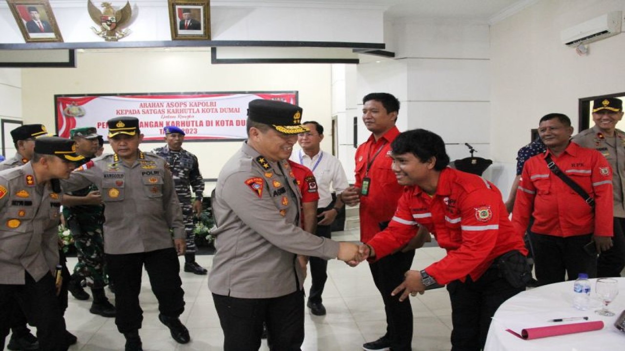 Asisten Operasional (Asops) Kapolri Irjen Pol Agung Setya Imam Effendi (kiri) bersalaman dengan seorang anggota Manggala Agni seusai memberikan arahan penanggulangan karhutla di Mapolres Dumai, Riau, Rabu (15/3/2023). (ANTARA/Aswaddy Hamid)