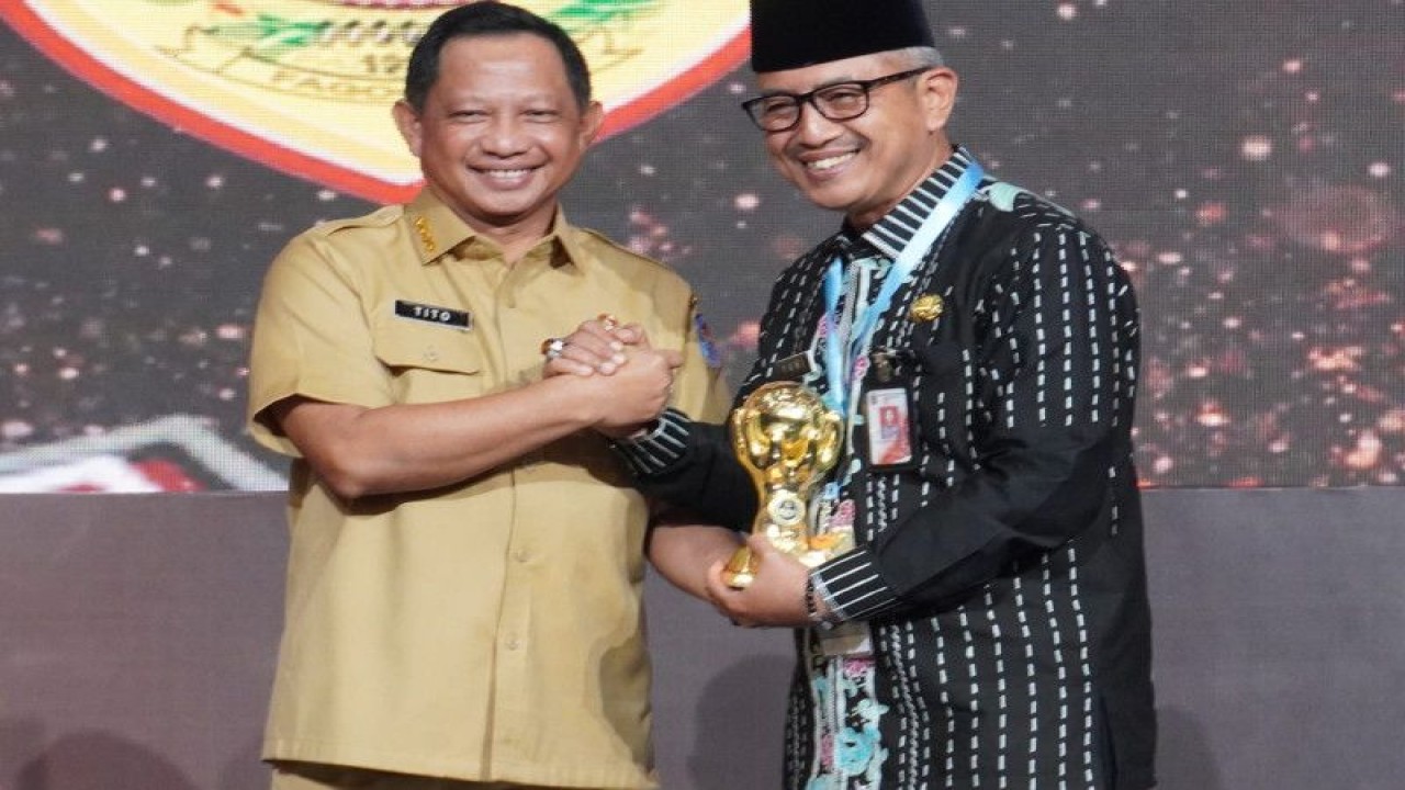 Menteri Dalam Negeri Tito Karnavian menyerakan penghargaan UHC kepada Wali Kota Jakarta Barat Yani Wahyu Purwoko di Jakarta, Selasa (14/3/2023). ANTARA/HO-Pemkot Jakarta Barat