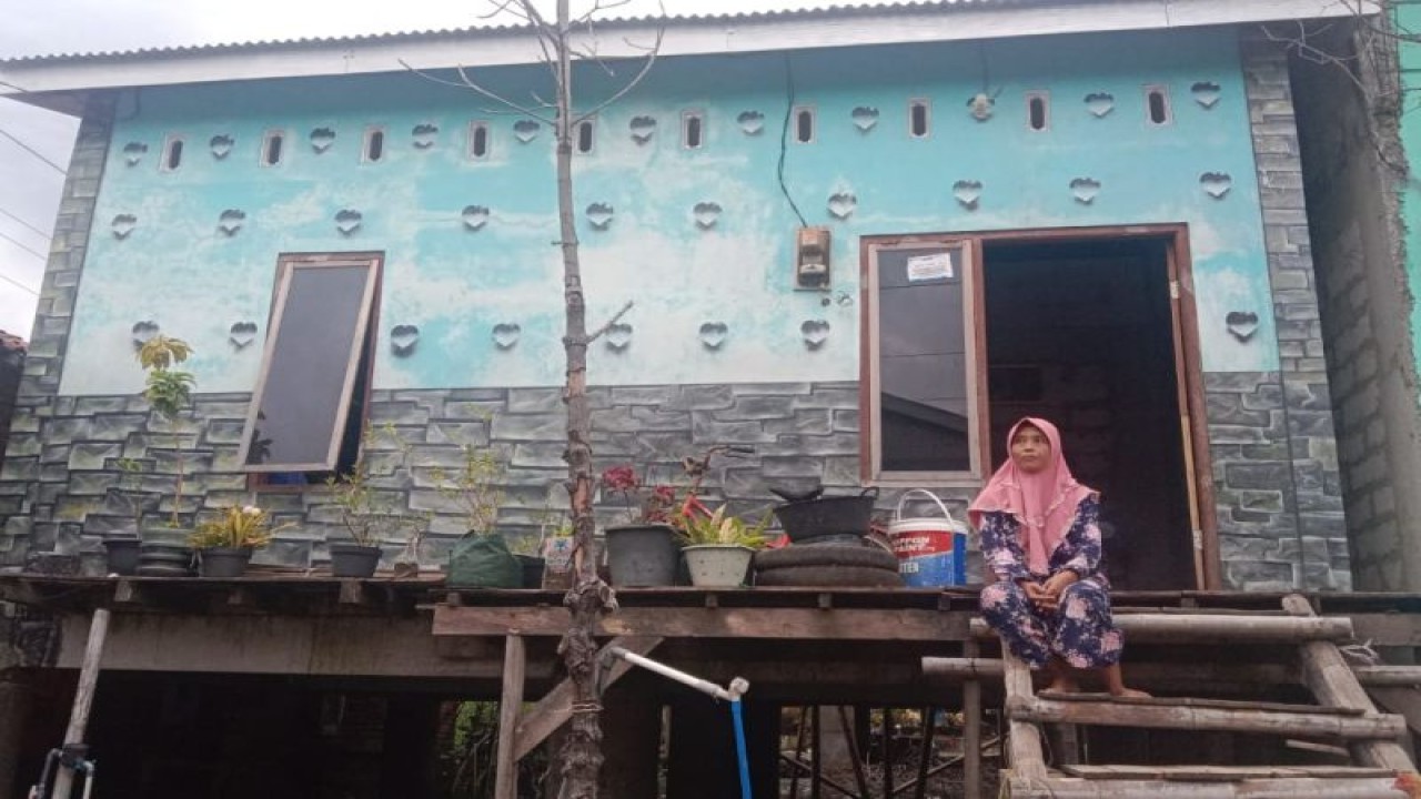 Salah seorang warga terdampak abrasi di Desa Bedono, Kecamatan Sayung, Kabupaten Demak, duduk di depan rumah bantuan Gubernur Jawa Tengah Ganjar Pranowo. (FOTO ANTARA/HO-Humas Pemprov Jateng)
