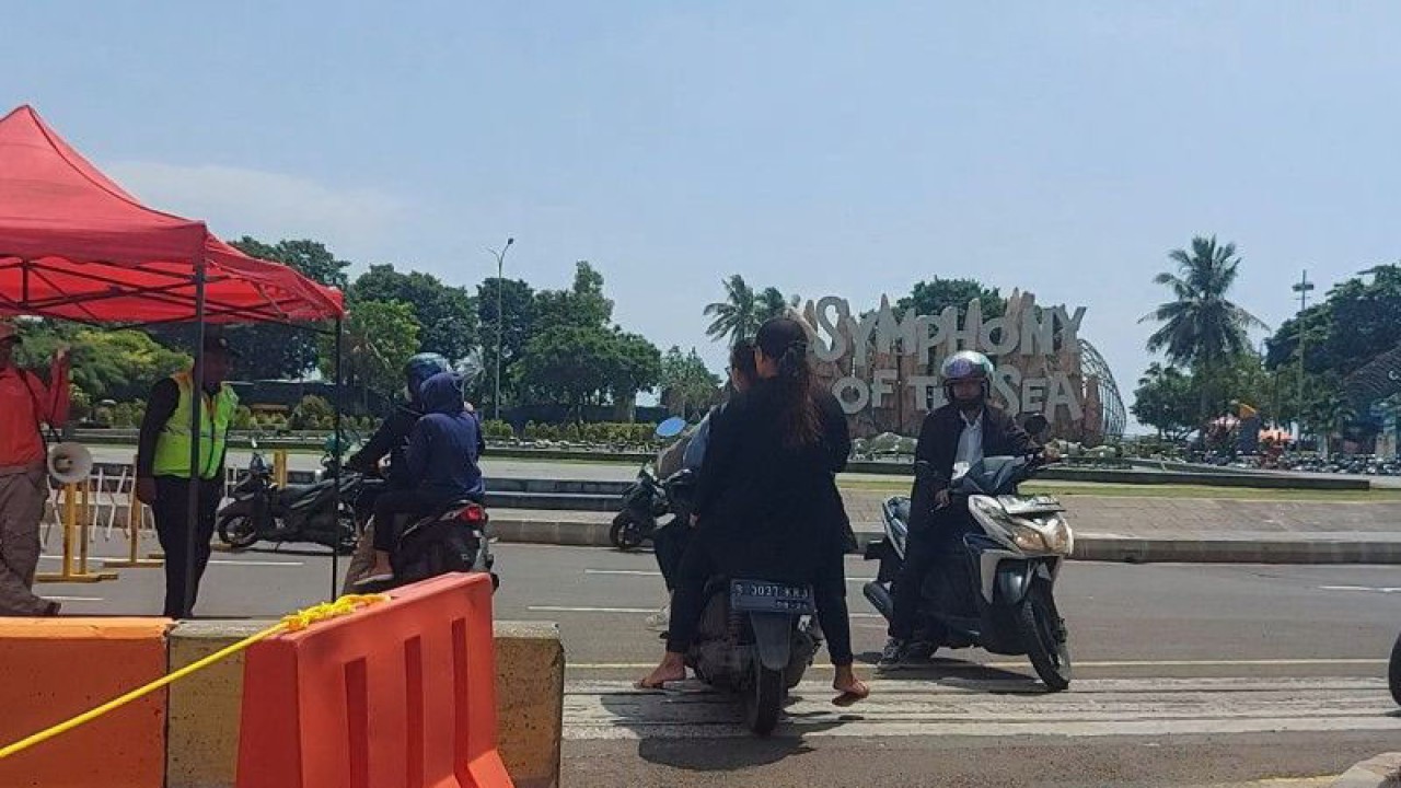 Petugas pengamanan dalam kawasan Taman Impian Jaya Ancol, Jakarta Utara mengarahkan pengunjung yang berkendara dengan sepeda motor ke arah tempat parkir sentral di bundaran air mancur area bebatuan Symphony of The Sea pada Minggu (23/4/2023). ANTARA/Abdu Faisal