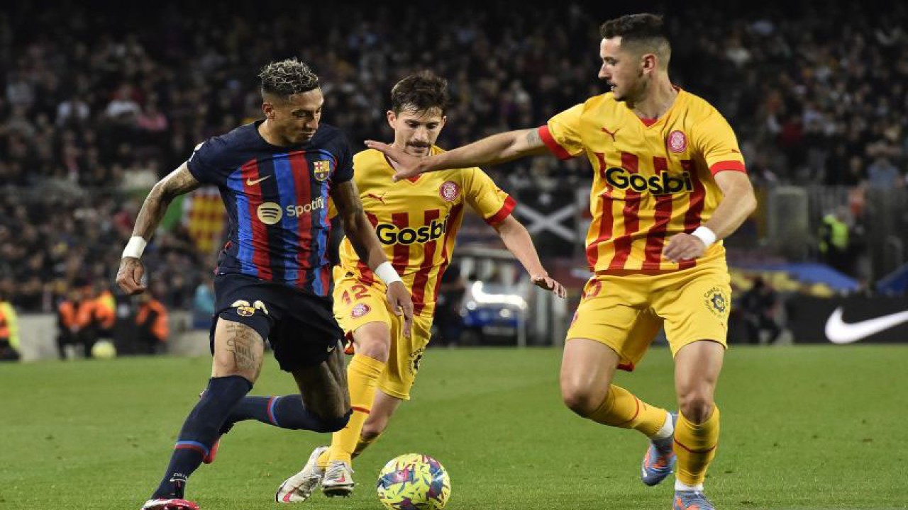 Penyerang Barcelona Raphinha (kiri) mencoba untuk melewati dua pemain Girona Toni Villa (tengah) dan Javier Hernandez dalam pertandingan Liga Spanyol melawan Girona di Camp Nou pada 11 April 2023. ANTARA/AFP/PAU BARRENA