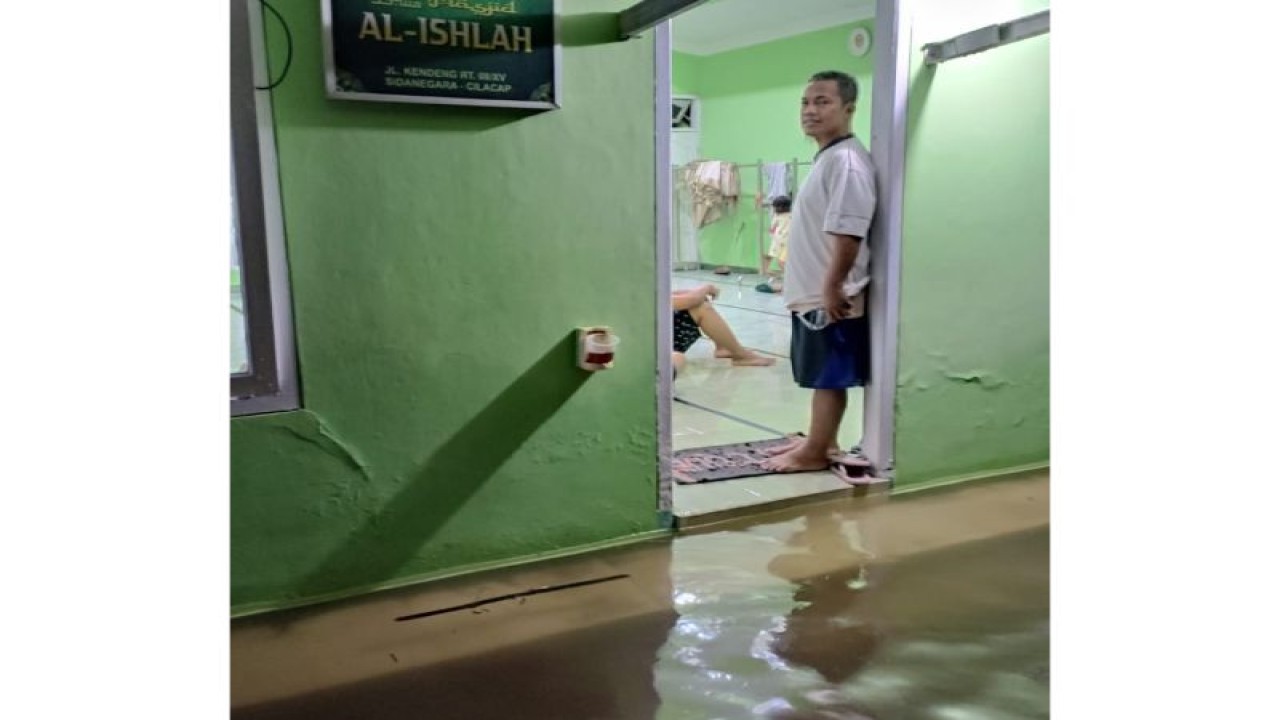 Salah seorang pengungsi memerhatikan genangan banjir di halaman Masjid Al Islah, Jalan Kendeng, Kelurahan Sidanegara, Kecamatan Cilacap Tengah, Kabupaten Cilacap, Kamis (27/4/2023) malam. ANTARA/HO-BPBD CIlacap