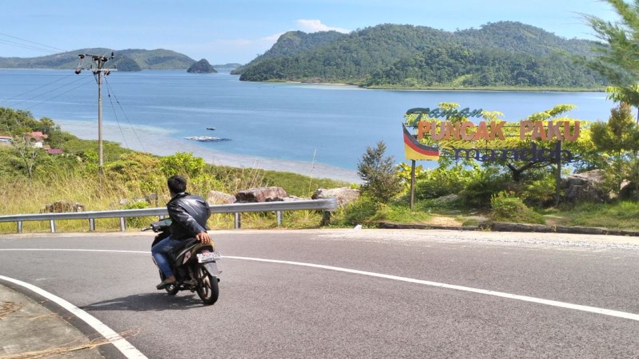 Warga melintas di objek wisata Puncak Paku yang berada di kawasan Puncak Mandeh, Kabupaten Pesisir Selatan, Minggu (9/4/2023). ANTARA/Muhammad Zulfikar.