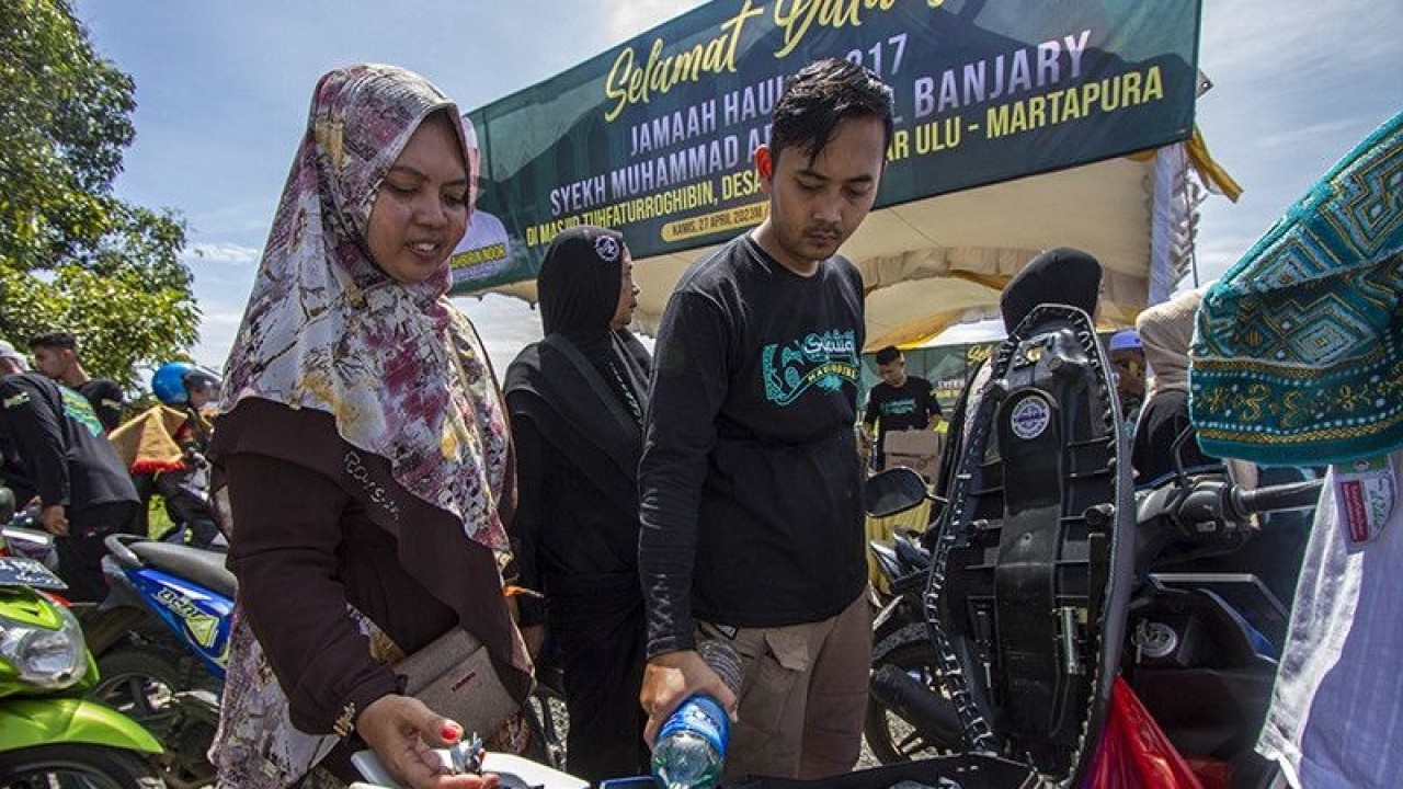 Relawan mengisikan bensin gratis yang dibagikan kepada Jamaah Puncak Haul Ke-217 Maulana Syekh Muhammad Arsyad Al Banjary (Datu Kalampayan) di Desa Dalam Pagar Ulu, Kabupaten Banjar, Kalimantan Selatan, Kamis (27/4/2023). Sebanyak seribu liter bensin jenis pertalite dibagikan relawan secara gratis kepada jamaah haul yang hadir pada Peringatan Haul Datu Kalampayan tersebut. ANTARA/Bayu Pratama S.