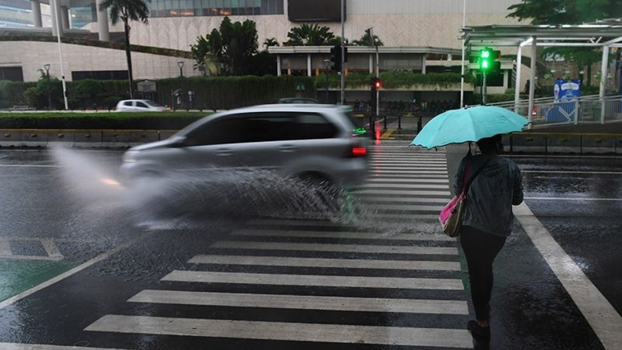 Arsip Foto - Warga berpayungan saat menyeberangi jalanan yang basah semasa hujan di Jakarta. (ANTARA FOTO/Akbar Nugroho Gumay/wsj)