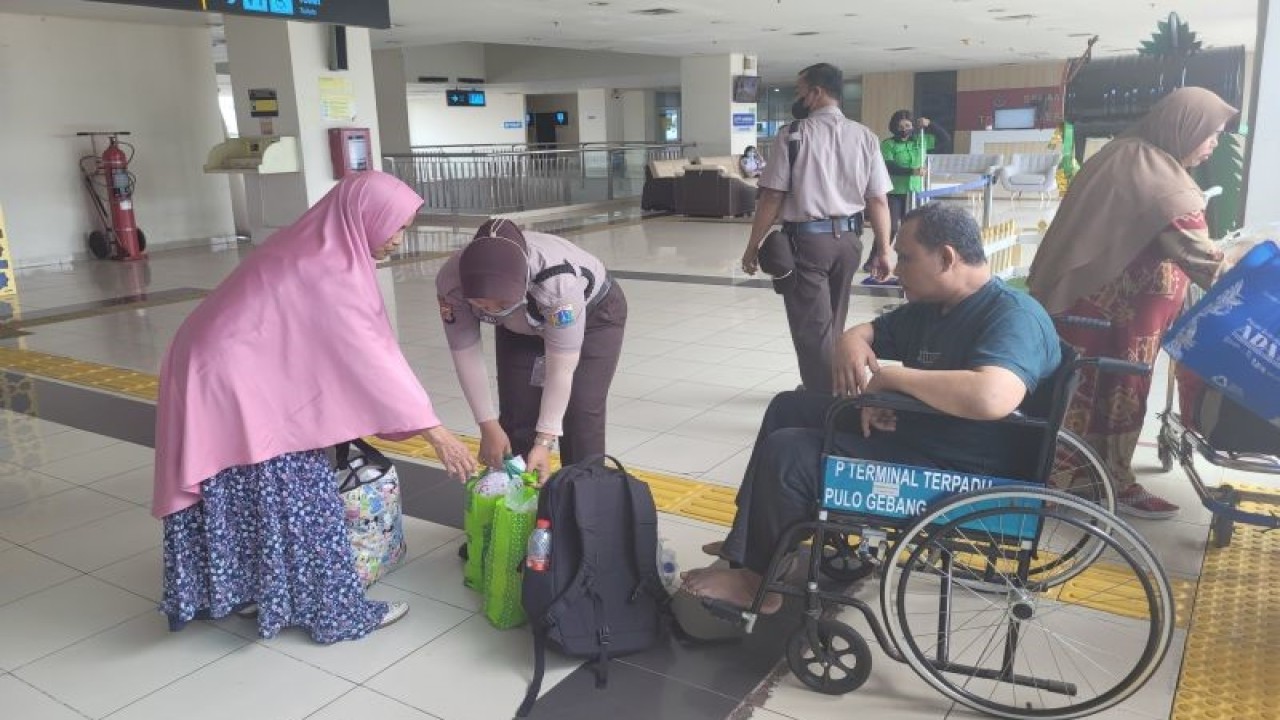 Petugas Terminal Terpadu Pulo Gebang yang sedang membantu pemilir disabilitas untuk membawakan barang setibanya di Jakarta, Selasa (25/4/23). (ANTARA/Sean Filo Muhamad)