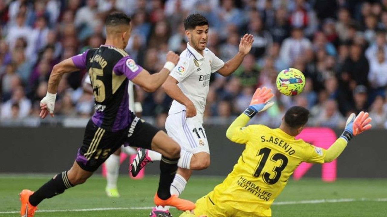 Pemain Real Madrid Marco Asensio berebut bola dengan pemain Real Valladolid Sergio Asenjo dalam pertandingan sepak bola lanjutan Liga Spanyol di Santiago Bernabeu, Madrid, Spanyol, Minggu (2/4/2023). Real Madrid menang dengan skor 6-0. ANTARA FOTO/Reuters/Isabel Infantes/nym.