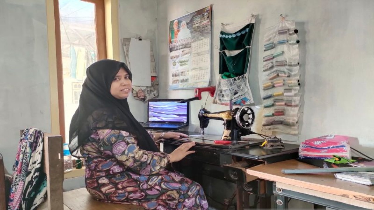 Muna Masyari saat berada di depan mesin jahit yang di sampingnya selalu terbuka laptop untuk mencatat jika muncul ide menulis cerpen di Pamekasan, Madura, Jawa Timur, beberapa waktu lalu. (Masuki M. Astro)