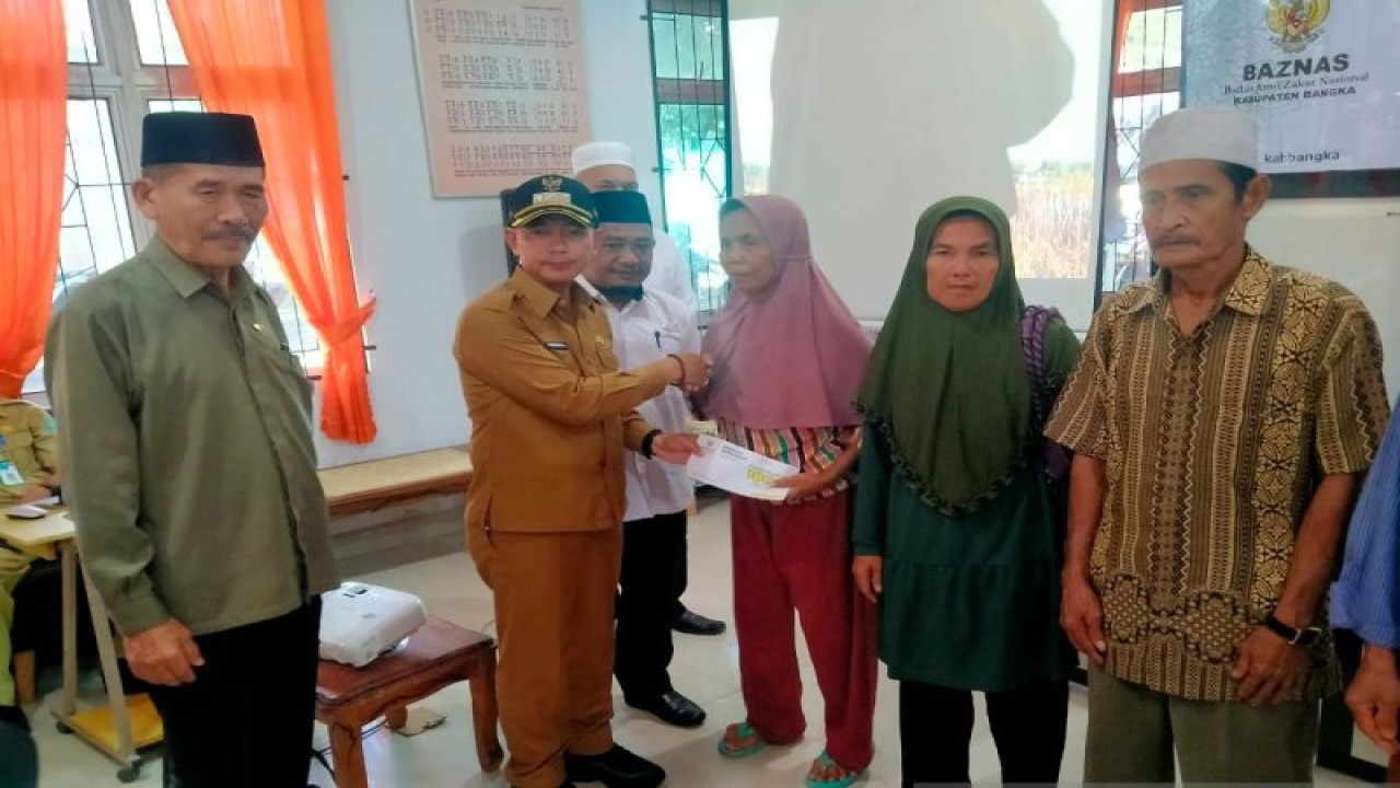 Bupati Bangka Mulkan didampingi Ketua Baznas Bangka M. Nasir Hasan menyerahkan bantuan sosial bagi masyarakat. (ANTARA/Kasmono)