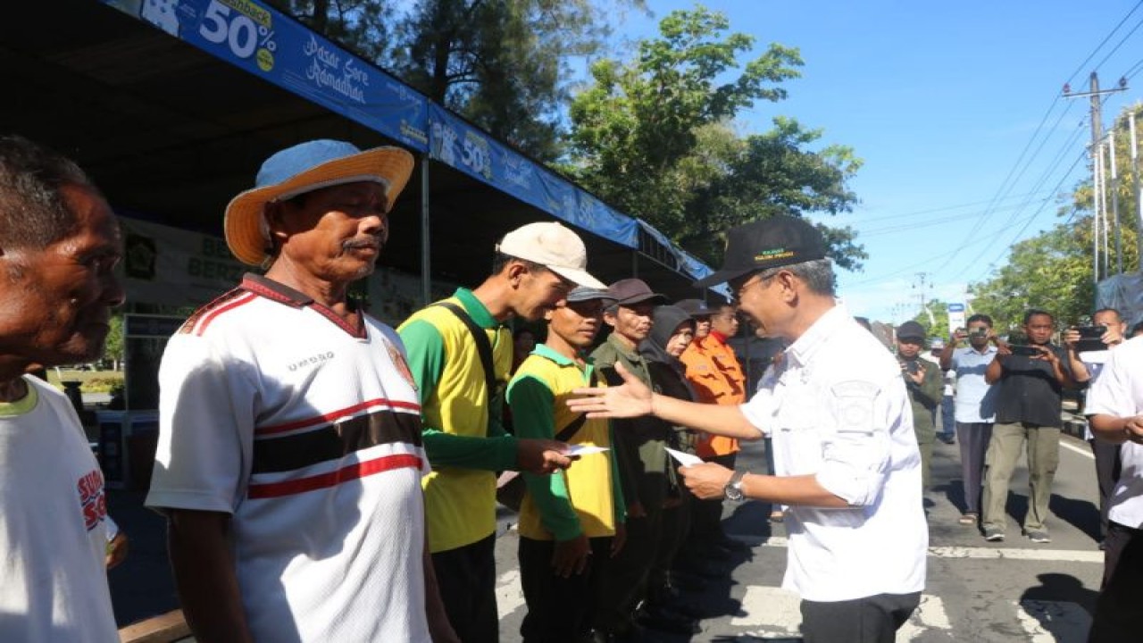 Penjabat Bupati Kulon Progo Tri menyerahkan bantuan kepada tukang bersih-bersih di kawasan Wates. (ANTARA/HO-Humas Pemkab Kulon Progo)