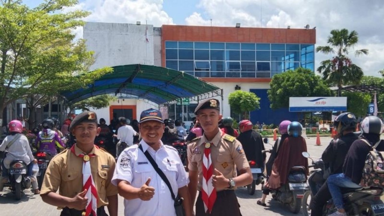 Supervisi PT ASDP Indonesia Ferry (Persero), Pelabuhan Penajam Cabang Balikpapan, Kalimantan Timur, Radmiadi berfoto bersama anggota Pramuka Saka Bahari dari Kwarcab Kabupaten Penajam Paser Utara berlatar belakang pemudik dengan kendaraan roda dua menggunakan jasa kapal feri. (ANTARA/Nyaman Bagus Purwaniawan)