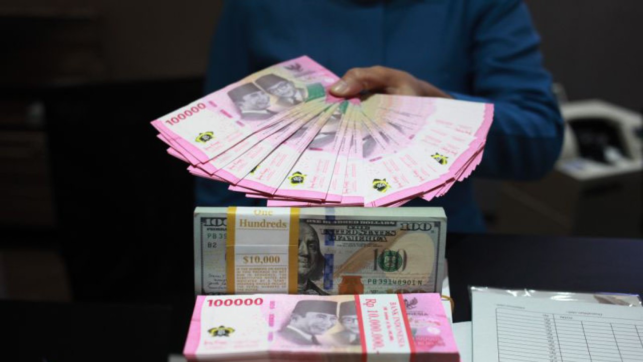 Petugas menunjukkan uang dolar AS dan uang rupiah di salah satu kantor cabang PT. Bank Mandiri Persero Tbk, Jakarta, Selasa (31/1/2023). ANTARA FOTO/Reno Esnir/tom