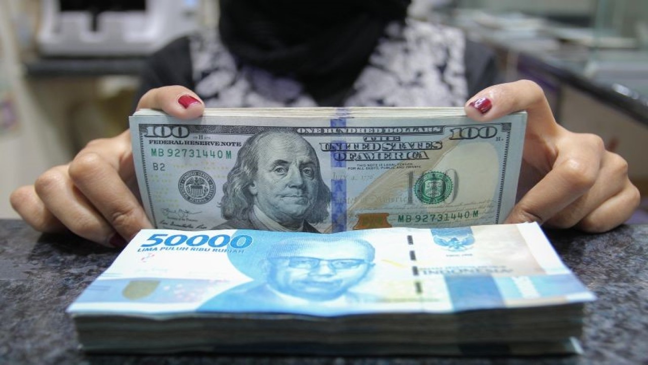 Pekerja menunjukkan uang dolar AS dan rupiah di salah satu gerai penukaran mata uang di Jakarta, Rabu (5/1/2022). ANTARA FOTO/Dhemas Reviyanto/wsj.