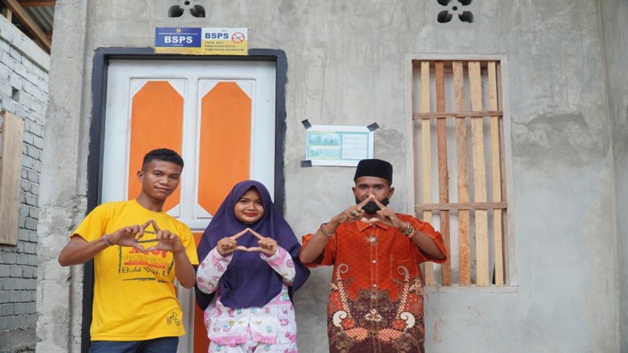 Masri dan anaknya berfoto bersama di depan rumah mereka yang telah diperbaiki dengan bantuan pemerintah melalui Program BSPS Tahun 2022. (ANTARA/HO-BP2P Sulawesi II)