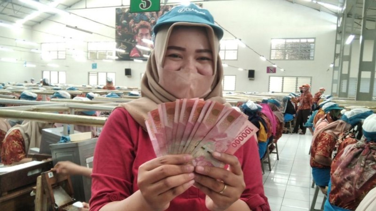 Seorang pekerja rokok tengah menunjukkan uang tunjangan hari raya (THR) yang baru diterima di brak Bitingan Lama Djarum Kudus, Jawa Tengah, Selasa (11/4/2023). (ANTARA/Akhmad Nazaruddin Lathif)