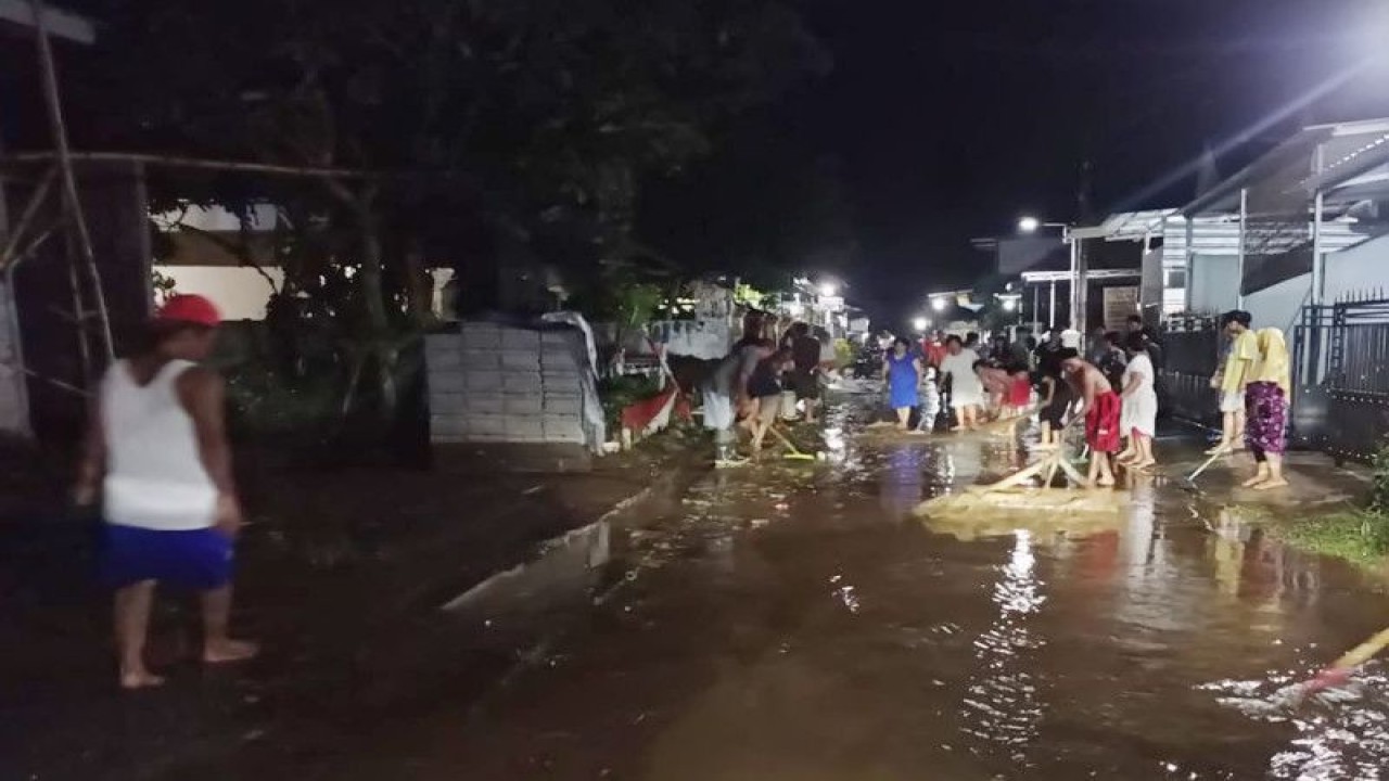 Petugas gabungan dan warga membersihkan akses jalan yang terendam banjir di Desa Kutorenon, Kecamatan Sukodono, Kabupaten Lumajang, Kamis (27/4/2023) malam. (ANTARA/HO-Diskominfo Lumajang)