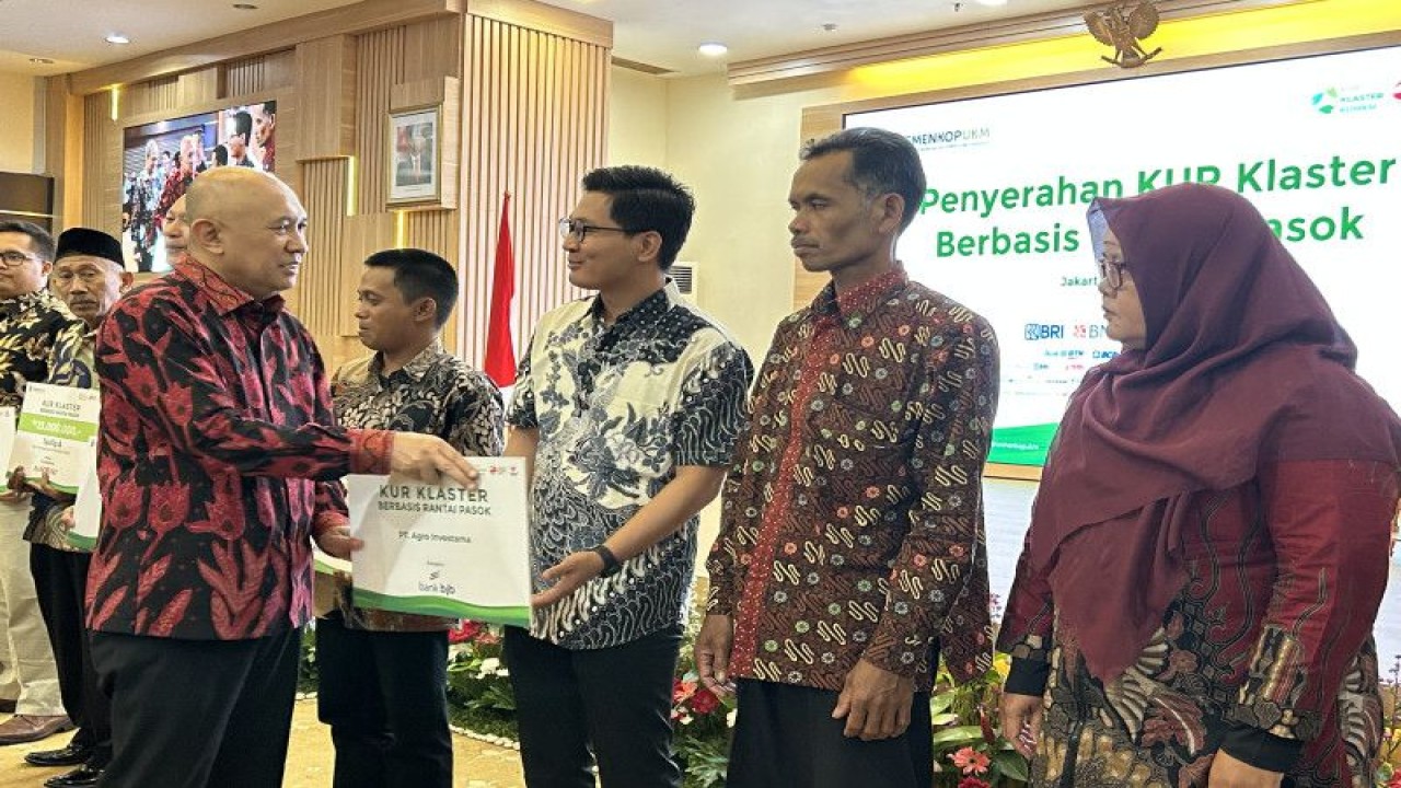Menteri Koperasi dan UKM Teten Masduki (kiri) secara simbolis memberikan KUR pada penerima KUR Klaster berbrasi rantai pasok pada Kegiatan Penyerahan KUR Klaster berbasis rantai pasok di Kantor KemenKopUKM, Jakarta, Rabu (12/4/2023). ANTARA/Kuntum Riswan.