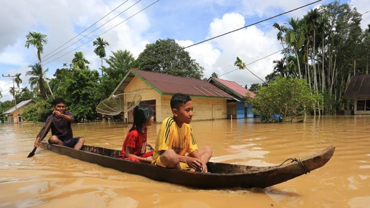 Warga bersama anaknya berusaha melintasi banjir dengan menggunakan perahu di Desa Napai, Woyla Barat, Aceh Barat, Aceh, Minggu (7/5/2023). Data Badan Penanggulangan Bencana Aceh (BPBA) menyebutkan, banjir yang disebabkan tingginya intensitas hujan menyebabkan meluapnya beberapa sungai di  Kabupaten Nagan Raya, Aceh Barat Daya, Aceh Barat, Aceh Selatan, Aceh Jaya, Aceh Tenggara, Aceh Singkil dan Kota Subulussalam sehingga ribuan rumah warga terendam dengan ketinggian air mencapai 60-150 cm. ANTARA FOTO/Syifa Yulinnas/nym.