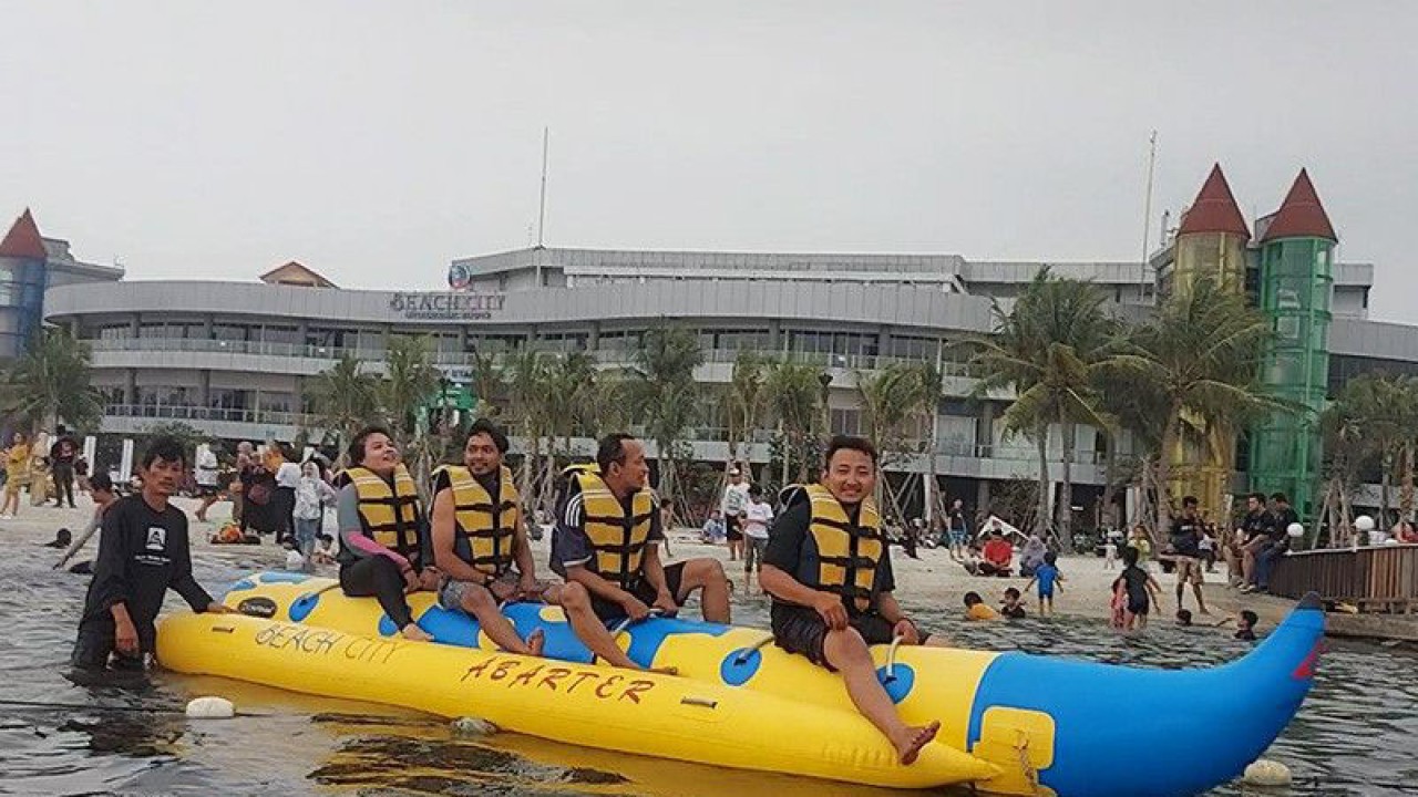 Empat pengunjung Taman Impian Jaya Ancol bermain perahu karet berbentuk memanjang (banana boat) di area Beach City International Stadium, Jakarta Utara, Minggu (21/5/2023). ANTARA/Abdu Faisal/aa.