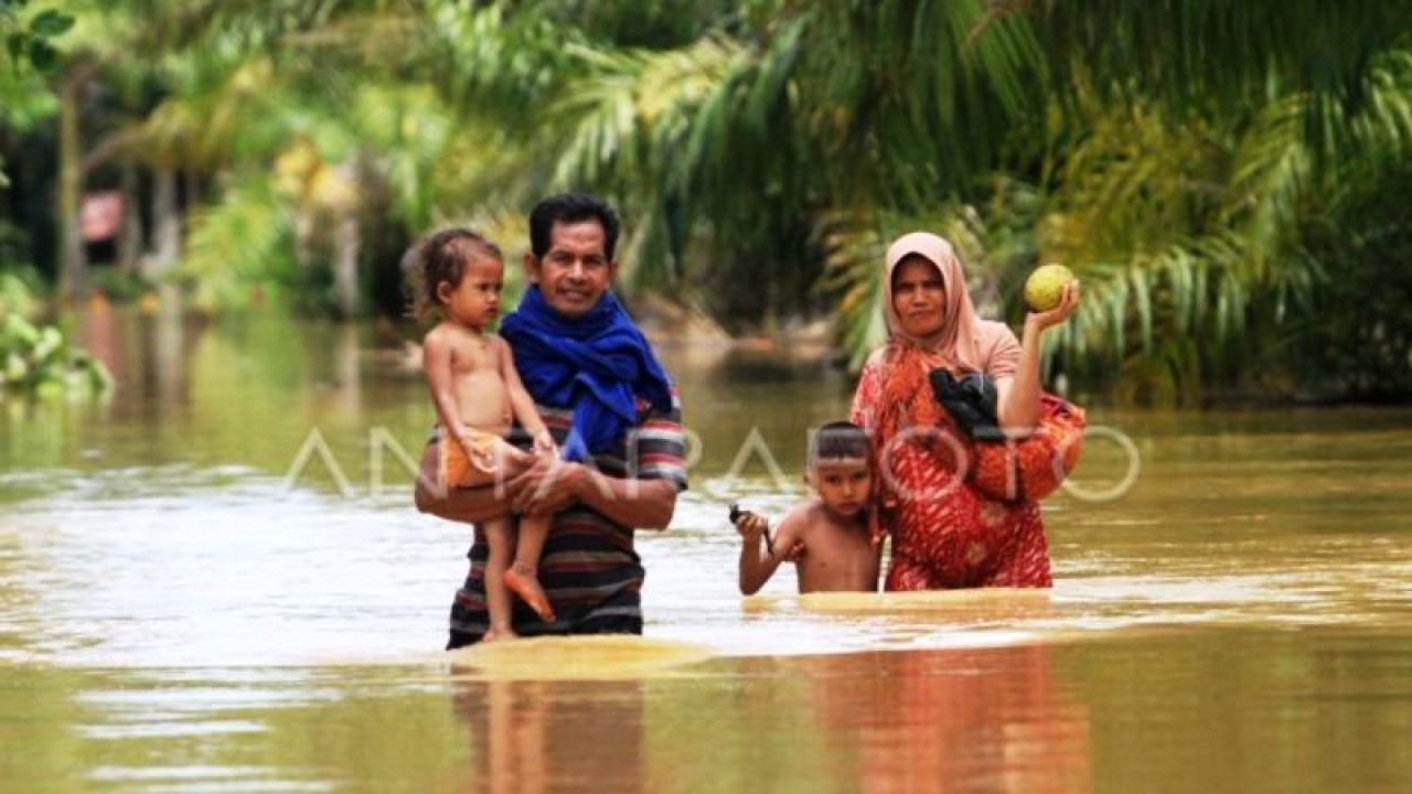 Dua warga bersama anaknya berusaha melintasi banjir di Desa Napai, Woyla Barat, Aceh Barat, Aceh, Minggu (7/5/2023). (ANTARA FOTO/Syifa Yulinnas/YU)