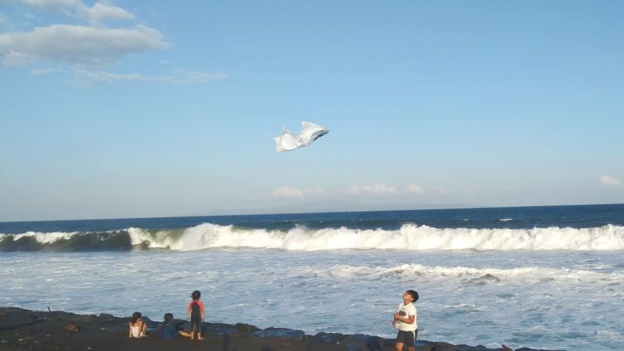Arsip foto - Seorang anak bermain layang-layang dengan latar ombak tinggi di Pantai Purnama, Kabupaten Gianyar, Bali, Kamis (14/5/2023) ANTARA/Dewa Ketut Sudiarta Wiguna
