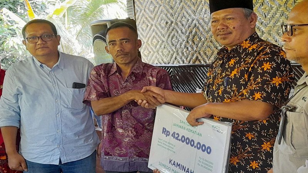 Kepala BPJAMSOSTEK Cabang Purwokerto Antony Sugiarto (kiri) menyaksikan penyerahan klaim jaminan sosial ketenagakerjaan kepada Julianto selaku ahli waris Kaminah pada acara Rapat Koperasi Semedo Manise Sejahtera di Balai Kelompok Tani Manggar Jaya, Desa Semedo, Rabu (24/5/2023). (ANTARA/HO-BPJAMSOSTEK Purwokerto)