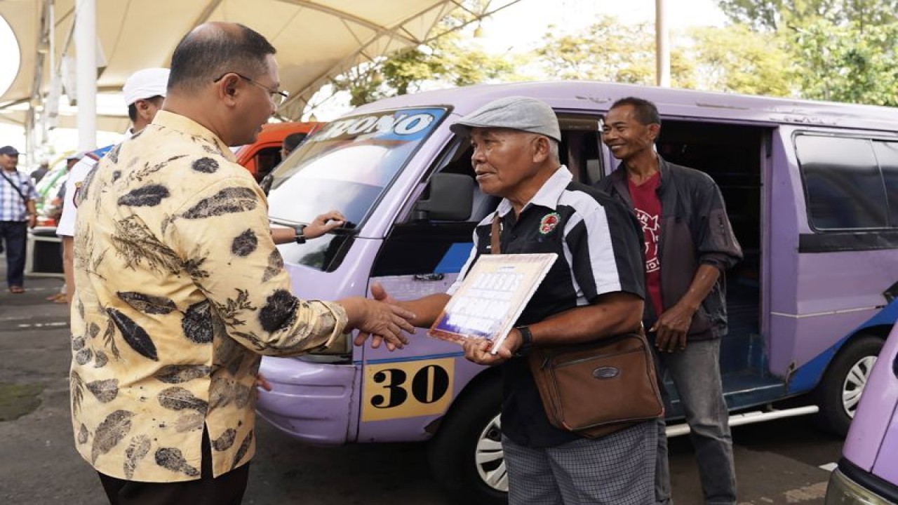 Penjabat (Pj) Wali Kota Batu Aries Agung Paewai (kiri) menyerahkan Bantuan Langsung Tunai (BPT) kepada salah satu pengemudi angkutan umum yang ada di Kota Batu, Jawa Timur, Kamis (4/5/2023). (ANTARA/HO-Humas Pemkot Batu)