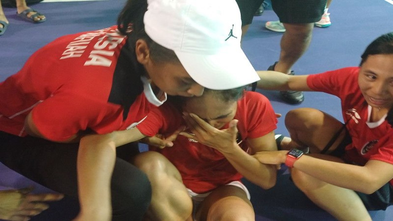 Dwi Rahayu Pitri yang terduduk sambil menyeka air mata dibantu rekan-rekannya untuk berdiri seusai memastikan meraih medali emas nomor tunggal putri SEA Games 2023 di Olympic Stadium Phnom Penh, Rabu (10/5/2023). ANYADA/DDN