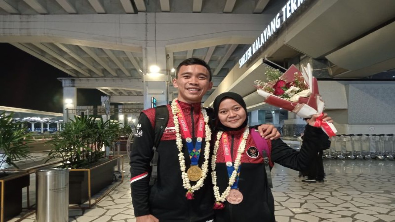 Atlet hoki indoor putra Fajar Jaelani Nugraha (kanan) dan atlet hoki indoor putri Aimelis Kusmiati (kiri) berfoto bersama di Bandara Soekarno-Hatta, Tangerang, Senin (8/5/2023). (ANTARA/RAUF ADIPATI)