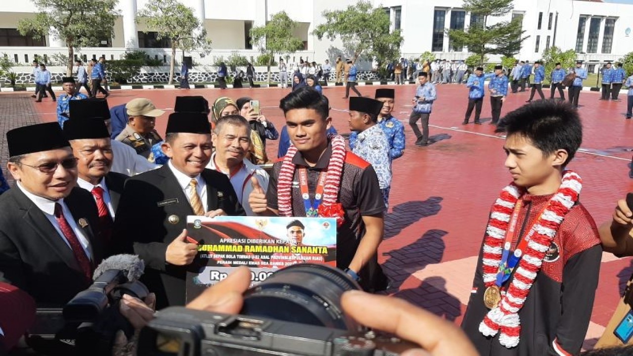 Gubernur Kepulauan Riau (Pemprov Kepri) Ansar Ahmad memberikan bonus uang tunai senilai Rp100 juta kepada dua atlet peraih medali emas SEA Games Kamboja tahun 2023 di halaman kantor gubernur, Dompak, Tanjungpinang, Senin (22/5/2023). (FOTO ANTARA/Ogen)