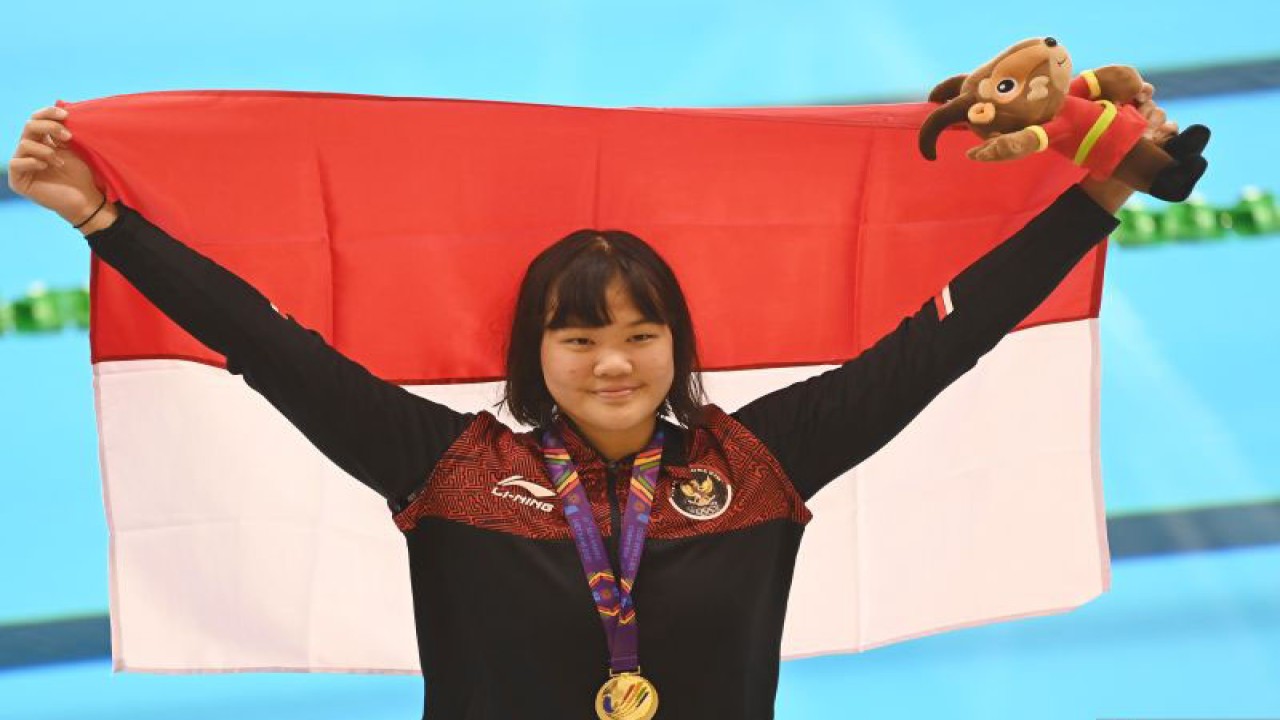 Arsip - Perenang Indonesia Flairene Candrea Wonomiharjo membentangkan bendera Merah Putih usai upacara pengalungan medali nomor renang 100 meter gaya punggung putri SEA Games 2021 Vietnam di Aquatic Sport Palace, Hanoi, Vietnam, Selasa (17/5/2022). . ANTARA FOTO/Aditya Pradana Putra/rwa.