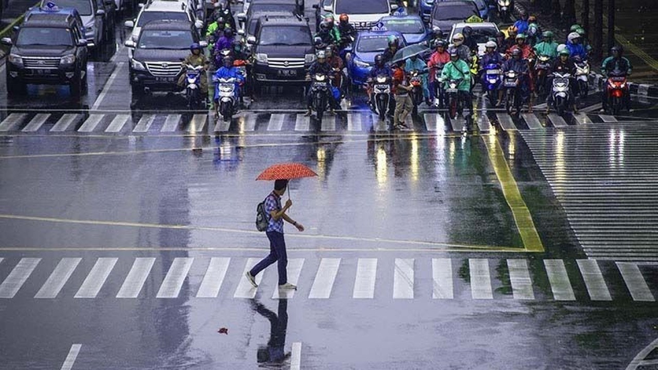 Arsip Foto - Seorang pekerja menggunakan payung untuk menghindari hujan saat menyeberang jalan di kawasan Jalan MH Thamrin, Jakarta. ANTARA/Aprillio Akbar/hp/aa.