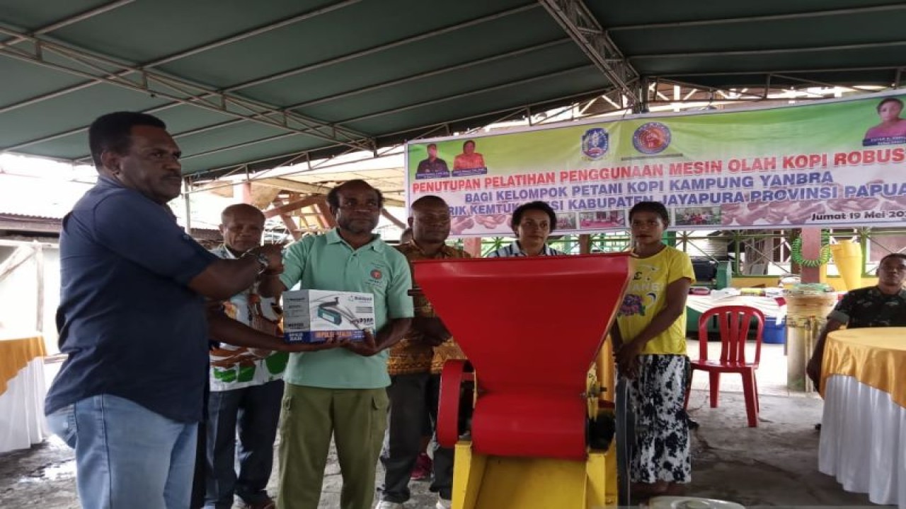 Kepala Dinas Perindustrian dan Perdagangan Kabupaten Jayapura Theopilus H. Tegai menyerahkan mesin mengupas biji kopi kepada petani Kampung Yanbra Distrik Kemtuk Gresi. (ANTARA/Agustina Estevani Janggo)