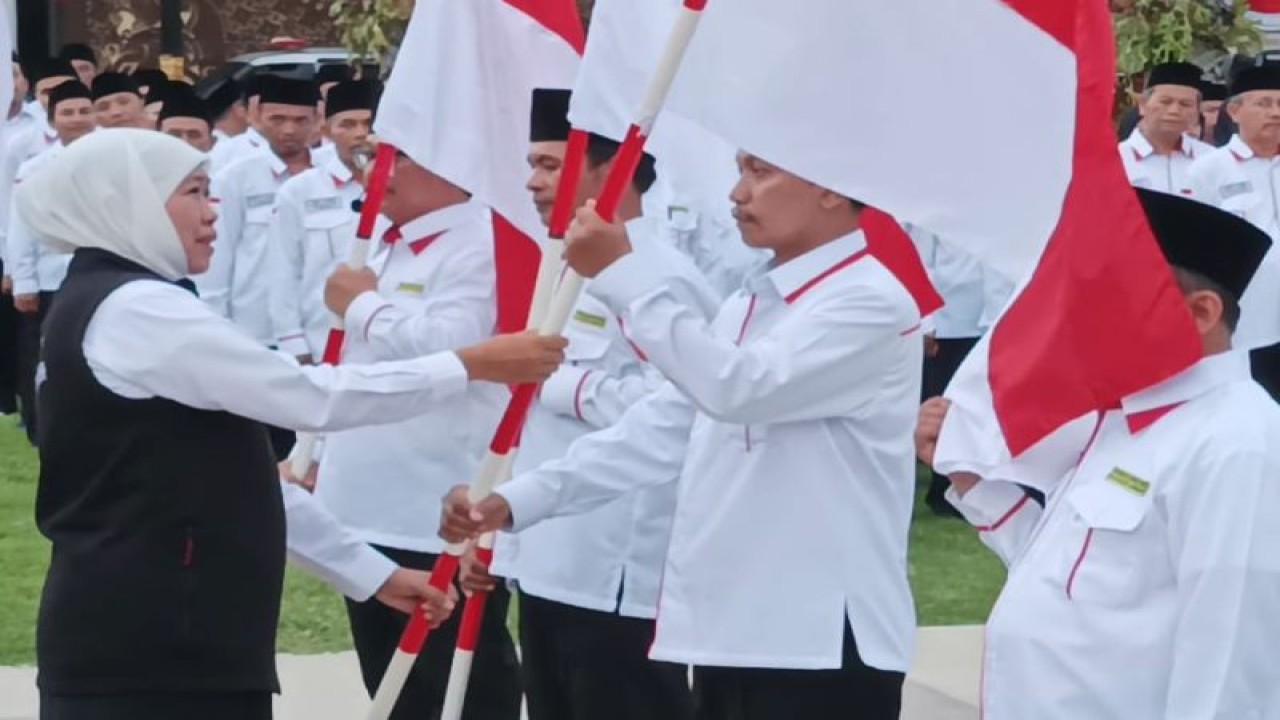 Gubernur Jatim Khofifah Indar Parawansa (kiri) secara simbolis menyerahkan bendera merah putih kepada koordinator petugas haji asal provinsi setempat saat apel kesiapsiagaan petugas haji Indonesia Embarkasi Surabaya di halaman Gedung Negara Grahadi Surabaya, Kamis petang (11/5/2023). (FOTO ANTARA/Hanif Nashrullah)