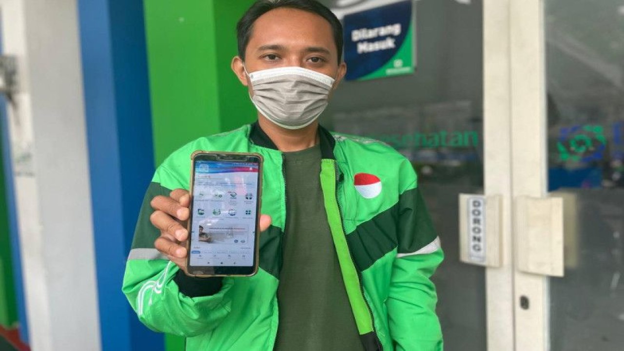 Pengemudi ojek online (ojol) bernama Faisal Irilesta asal Gresik, Jawa Timur, menunjukkan aplikasi mobile JKN (ANTARA/HO/Sugiharto Purnama)