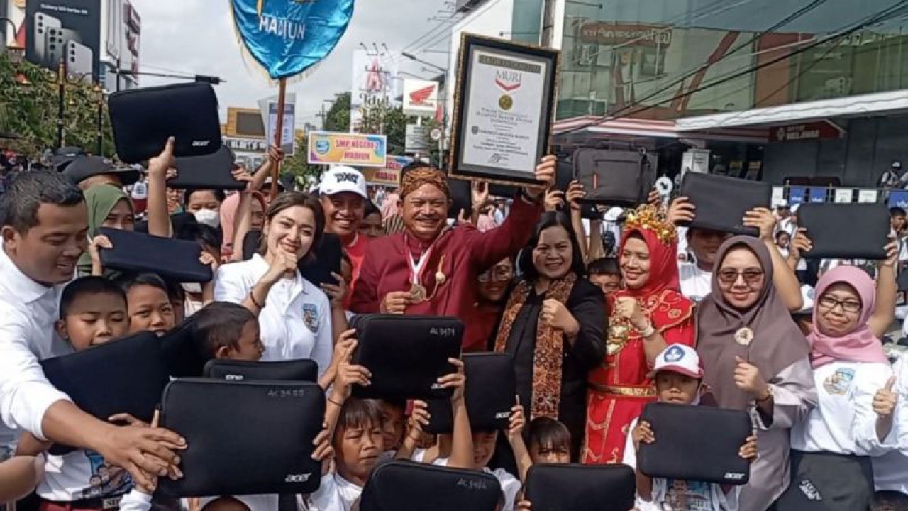 Wali Kota Maidi menerima sertifikat penghargaan MURI atas penyerahan laptop gratis bagi siswa siswa SD dan SMP sebanyak 9.400 unit dari MURI Representative Sri Widayati didampingi para siswa bertepatan dengan peringatan Hari Pendidikan Nasional di kawasan Pahlawan Street Center (PSC) Madiun, Selasa (2/5/2023). ANTARA/Louis Rika