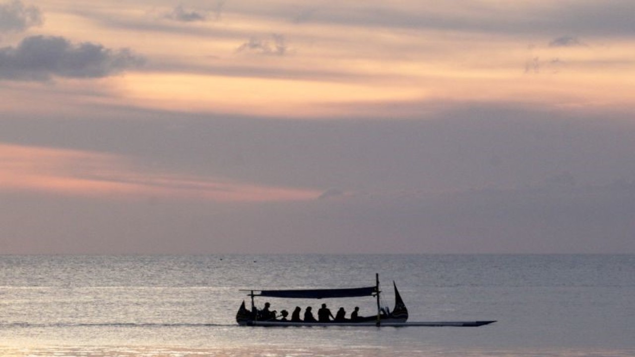 Pemgunjung Wisata Bahari Pasir Putih Situbondo menaiki perahu wisata sambil menikmati matahari terbenam. ANTARA/Novi Husdinariyanto