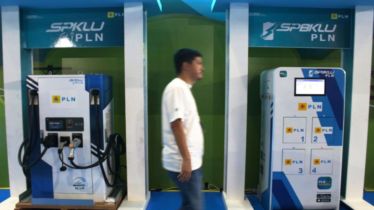 Seorang melintas di antara model unit Stasiun Pengisian Kendaraan Listrik Umum (SPKLU) dan Stasiun Penukaran Baterai Kendaraan Listrik Umum (SPBKLU) di PEVS 2023, Rabu (17/5). (ANTARA/Ahmad Faishal)