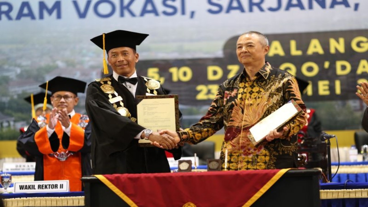 Rektor Universitas Muhammadiyah Malang (UMM) Dr. Fauzan (memakai toga) bersama pengusaha asal Makau yang juga President Director OBOR Education Foundation, Soe To Tie Lin saat bertukar cinderamata di sela wisuda mahasiswa kampus setempat di Dome UMM, Selasa (23/5) (ANTARA/HO/UMM/End)