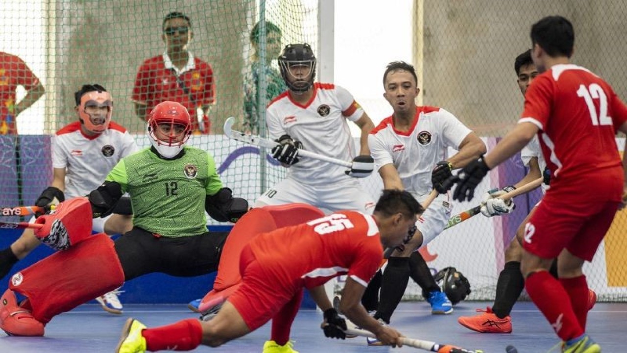 Atlet Hoki Indoor putra Indonesia berusaha mengadang serangan pemain Hoki Singapura M Shafiq Abdul R (kedua kanan) saat pertandingan grup SEA Games 2023 di Phnom Penh, Kamboja, Senin (1/5/2023). Tim Hoki putra Indonesia berhasil menang dengan skor 7-0. ANTARA FOTO/M Agung Rajasa/pras.