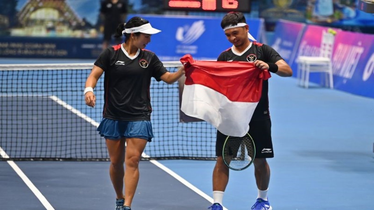 Arsip - Petenis Indonesia Aldila Sutjiadi (kiri) dan Christopher Rungkat (kanan) membawa bendera Merah Putih usai mengalahkan lawannya asal Thailand Patcharin Cheapchandej dan Pruchya Isaro pada babak final nomor ganda campuran tenis SEA Games 2021 Vietnam di Hanaka Paris Ocean Park, Bac Ninh, Vietnam, Jumat (20/5/2022). ANTARA FOTO/Aditya Pradana Putra/foc.