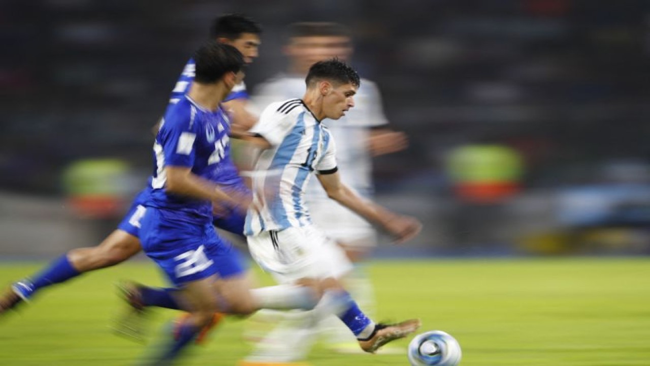 Pemain Argentina Brian Aguirre (tengah) mencoba melewati pemain Uzbekistan dalam pertandingan Grup A Piala Dunia u-20 di Estadio Unico Madre de Ciudades pada 20 Mei 2023. REUTERS/AGUSTIN MARCARIAN