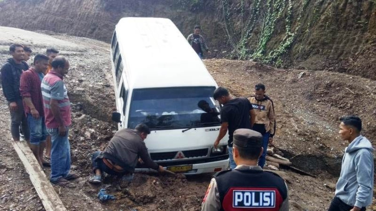 Masyarakat bersama petugas kepolisian membantu mengevakuasi satu unit angkutan umum yang terperosok tanah longsor di Jalan Provinsi di lintasan Kabupaten Aceh Barat-Kabupaten Pidie kawasan Simpang Baibon, Kecamatan Sungai Mas, Kabupaten Aceh Barat, Senin (8/5/2023). (ANTARA/HO)