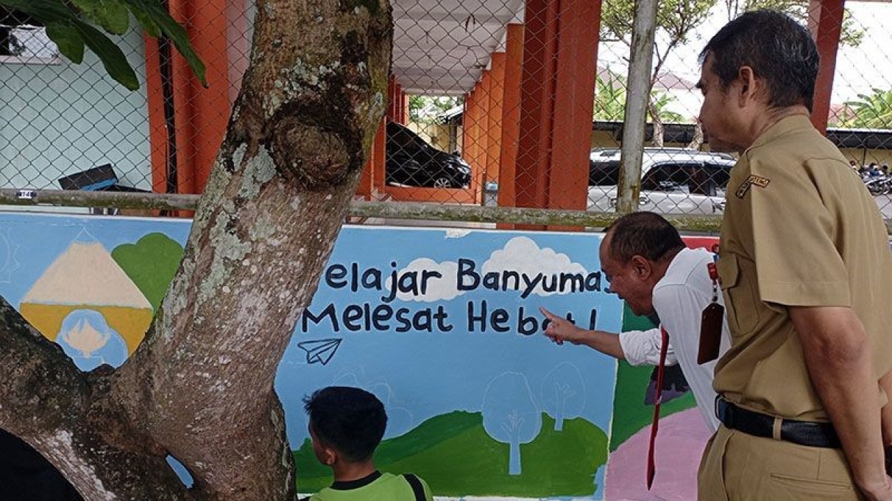 Wakil Bupati Banyumas Sadewo Tri Lastiono (dua dari kanan) didampingi Kepala Dinas Pendidikan Kabupaten Banyumas Joko Wiyono (kanan) berdialog dengan Tim SMP Negeri 1 Rawalo terkait mural yang mereka lukis pada dinding lapangan tenis Kantor Dinas Pendidikan Kabupaten Banyumas, Senin (22/5/2023). ANTARA/Sumarwoto