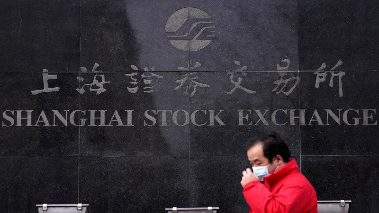 Seorang pria menggunakan masker saat berjalan melewati gedung Bursa Saham Shanghai di distrik keuangan Pudong di Shanghai, China, Senin (3/2/2020). REUTERS/Aly Song/wsj/djo.