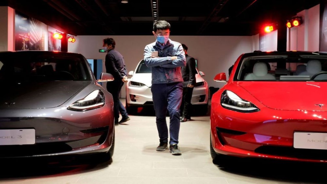 Seorang pria sedang berjalan diantara sedan Tesla Model 3 dan kendaraan sport Tesla Model X di ruang pamer Tesla di Shanghai, China, 8 Mei 2020. (Yilei Sun/Reuters)