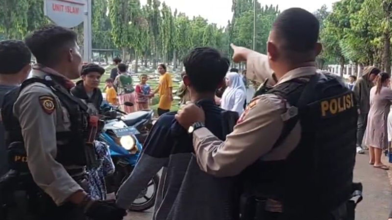 Dua personel Tim Perintis Presisi Polres Metro Jakarta Timur menangkap salah satu pelajar yang diduga akan tawuran di Taman Pemakaman Umum (TPU) Malaka II, Rawa Wadas, Kelurahan Pondok Kopi, Kecamatan Duren Sawit, Jakarta Timur, Selasa (23/5/2023). ANTARA/Syaiful Hakim