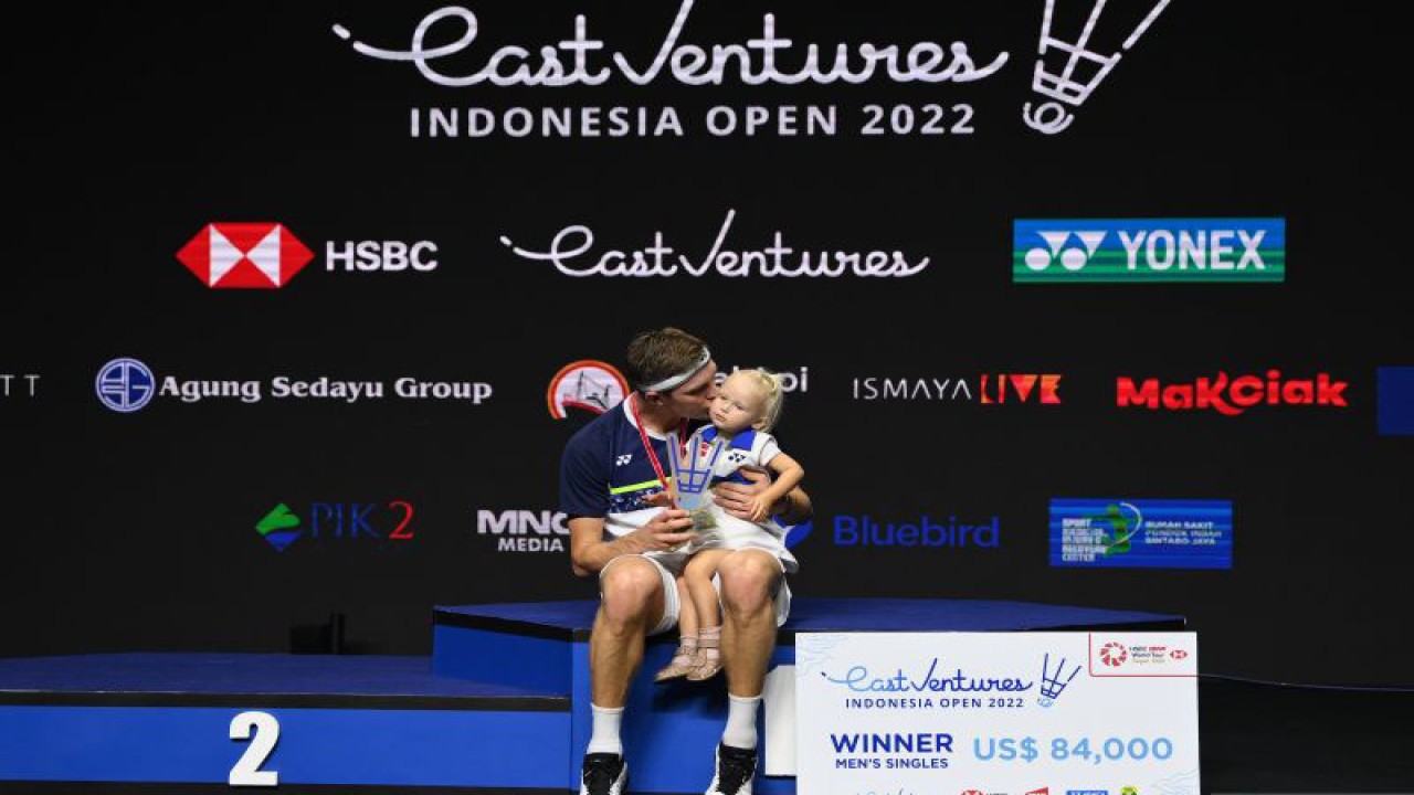 Pebulu tangkis tunggal putra Denmark Viktor Axelsen mencium anaknya di atas podium usai menjuarai final Indonesia Open 2022 di Istora Senayan, Jakarta, Minggu (19/6/2022). Viktor Axelsen berhasil menjadi juara usai mengalahkan tunggal putra China Zhao Jun Peng 21-9, 21-10. ANTARA FOTO/Sigid Kurniawan/nym. (ANTARA FOTO/SIGID KURNIAWAN)