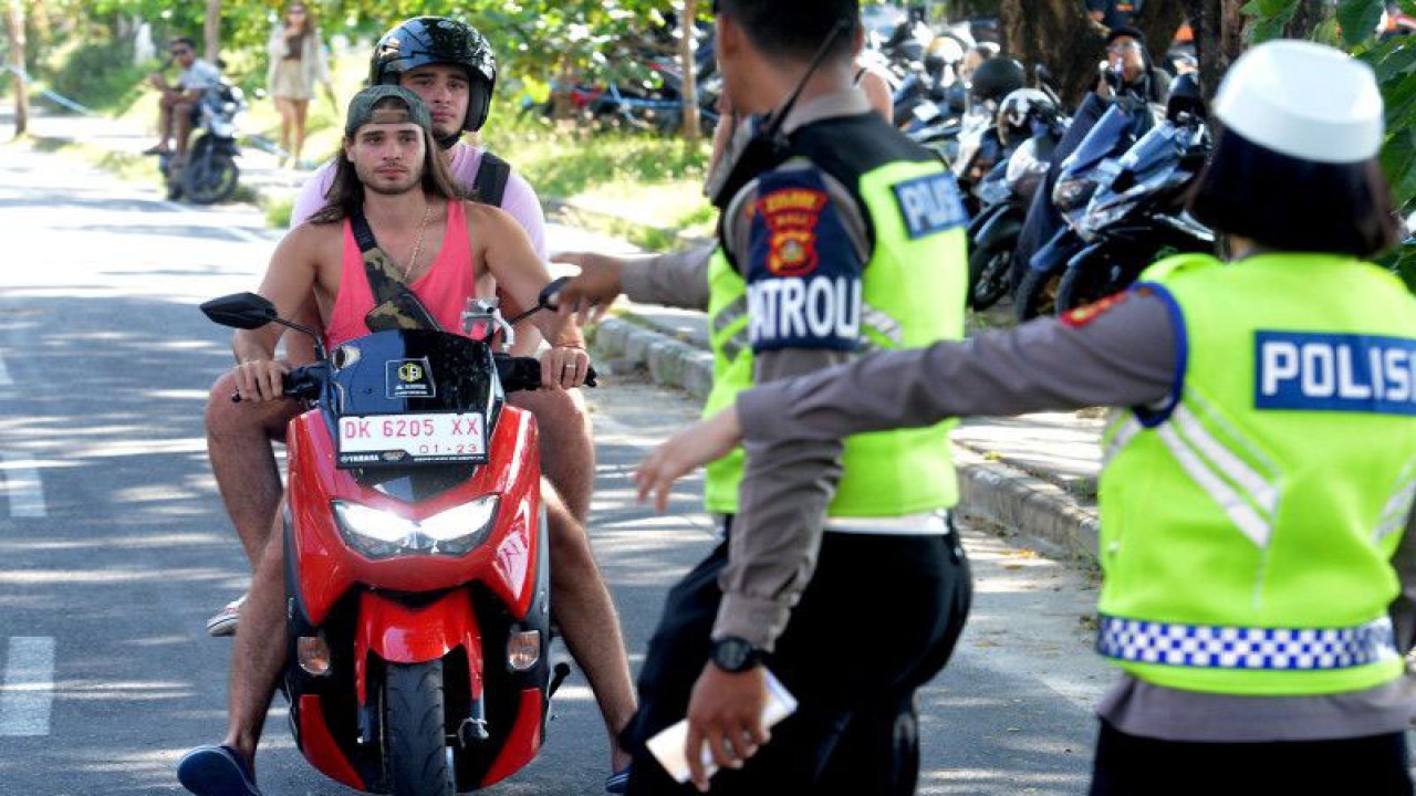 Personel Satlantas Polres Badung menghentikan warga negara asing (WNA) yang melanggar aturan lalu lintas di kawasan Canggu, Badung, Bali, Kamis (9/3/2023). Jajaran Polda Bali terus melakukan penindakan berupa tilang manual di berbagai titik kawasan wisata di Pulau Dewata menyusul maraknya WNA yang melanggar aturan berlalu lintas. ANTARA FOTO/Fikri Yusuf/aww.