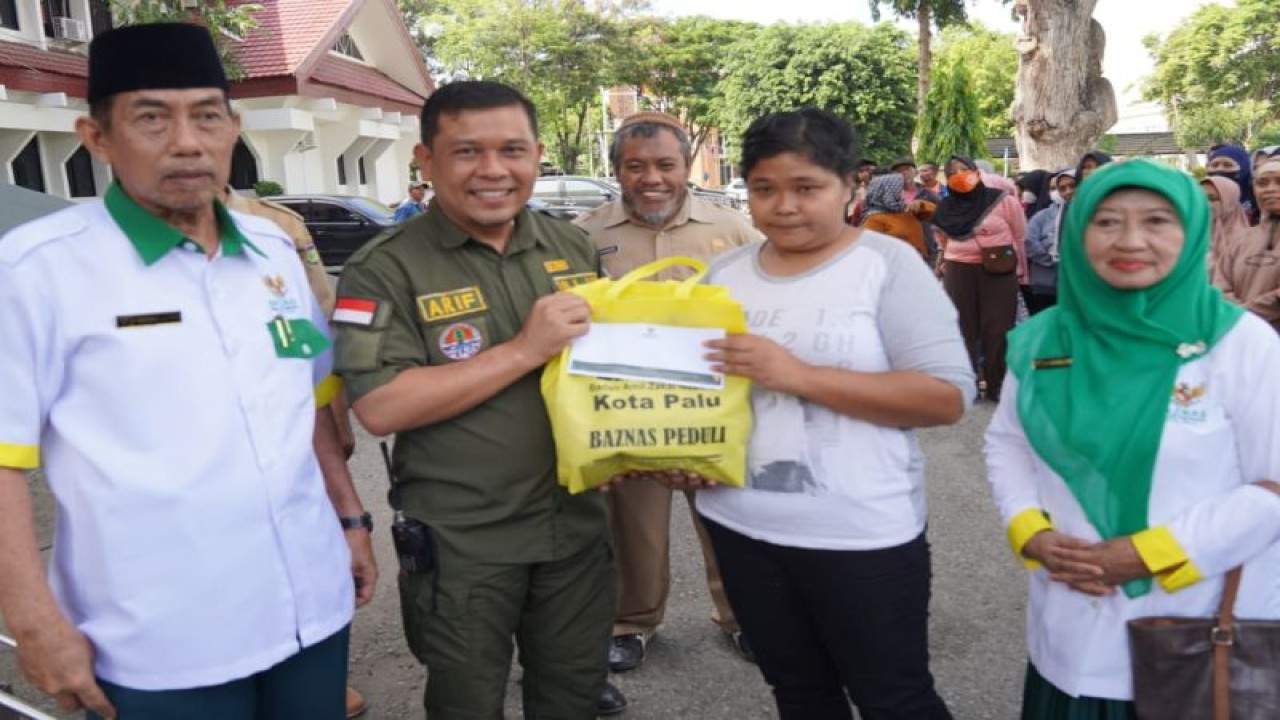 Kepala Dinas Lingkungan Hidup (DLH) Kota Palu, Moh Arif (kedua kiri) menyerahkan paket bantuan pangan kepada petugas kebersihan penyapu jalan yang diinisiasi Badan Amil Zakat Nasional (BAZNAS) setempat di Palu, Selasa (27/6/2023). ANTARA/HO-Humas Pemkot Palu